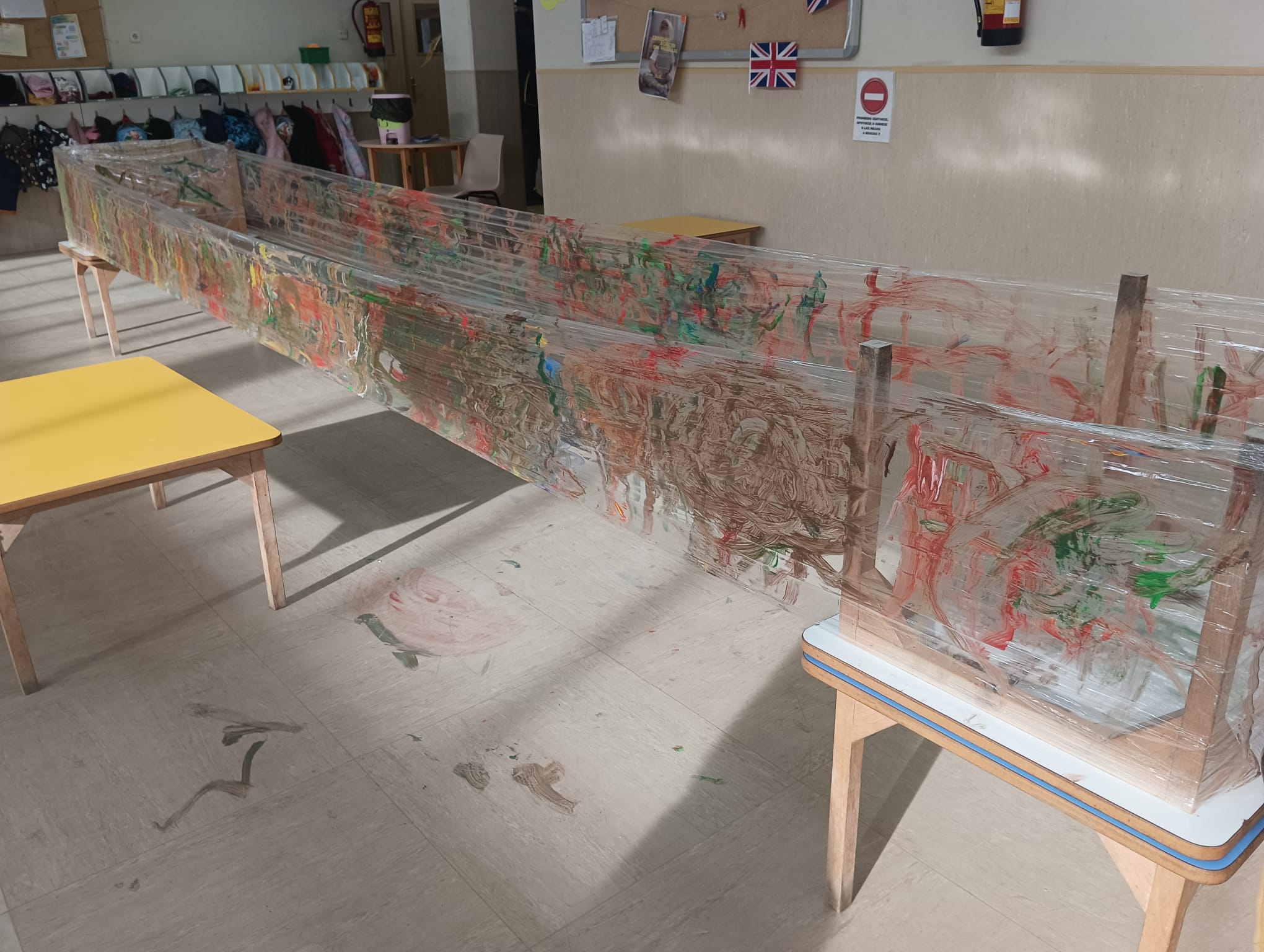 Mural de gran formato hecho con papel film pintado con colores vivos por alumnos de educación infantil.