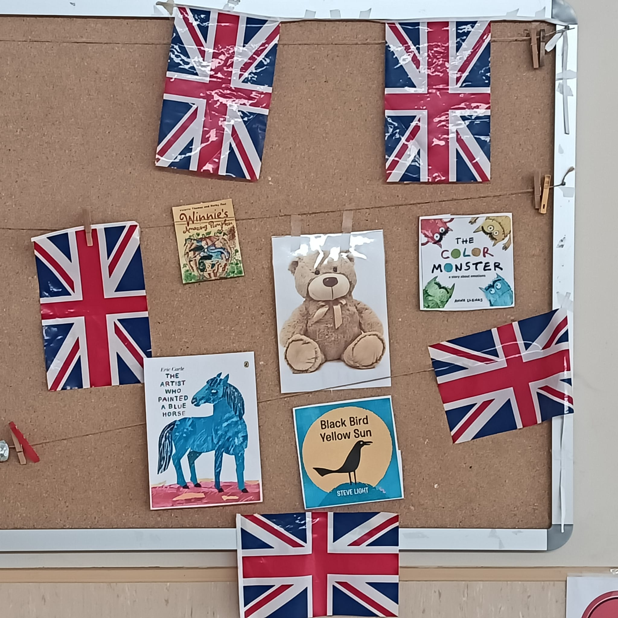 Tablón de anuncios con banderas del Reino Unido y portadas de cuentos en inglés para alumnos de educación infantil.
